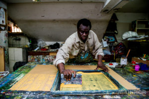 Wilson, a Sudanese refugee artist, works on a silkscreen in the basement of the All Saints Cathedral in Cairo in 2016.